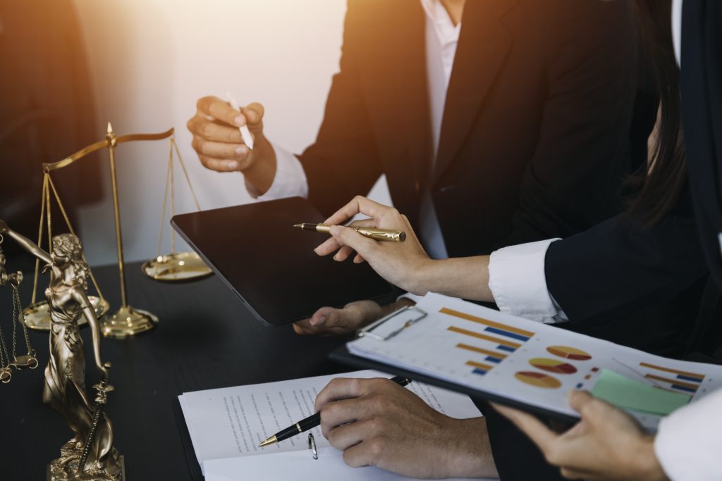 Dois empresários discutindo documentos financeiros e gráficos em uma mesa, cena comum ao realizar o Planejamento Tributário.