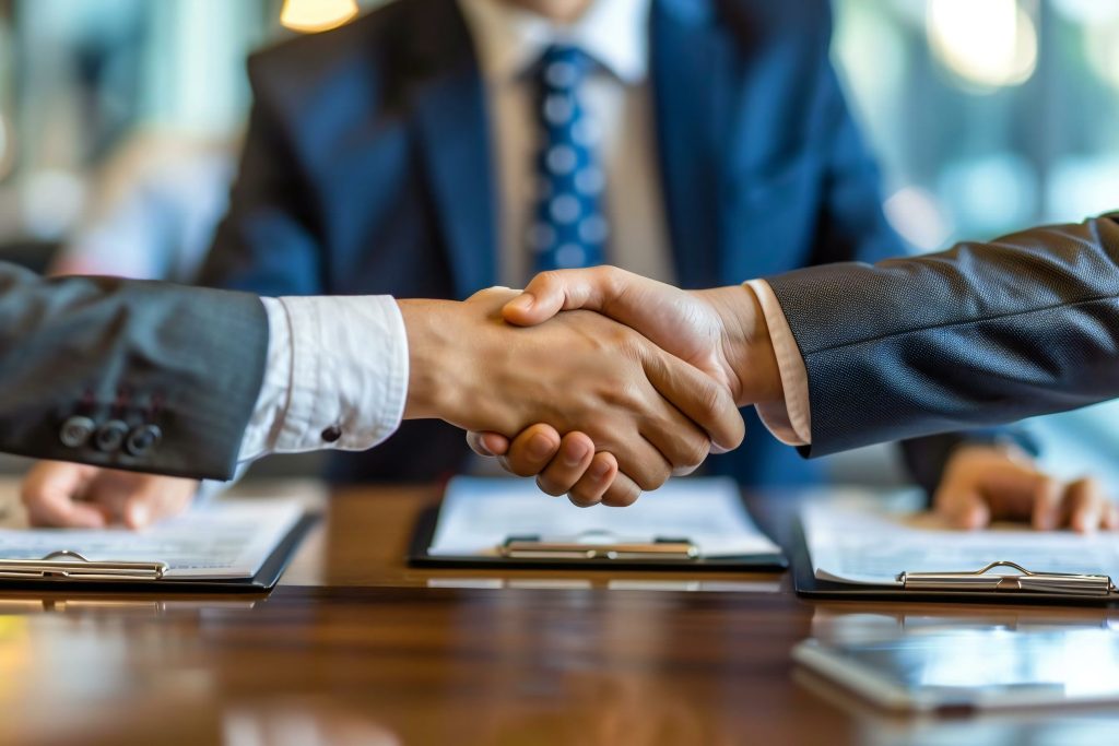 Dois empresários apertando as mãos sobre uma mesa, significando um acordo comercial ou parceria, um tema central no Direito empresarial para varejo.