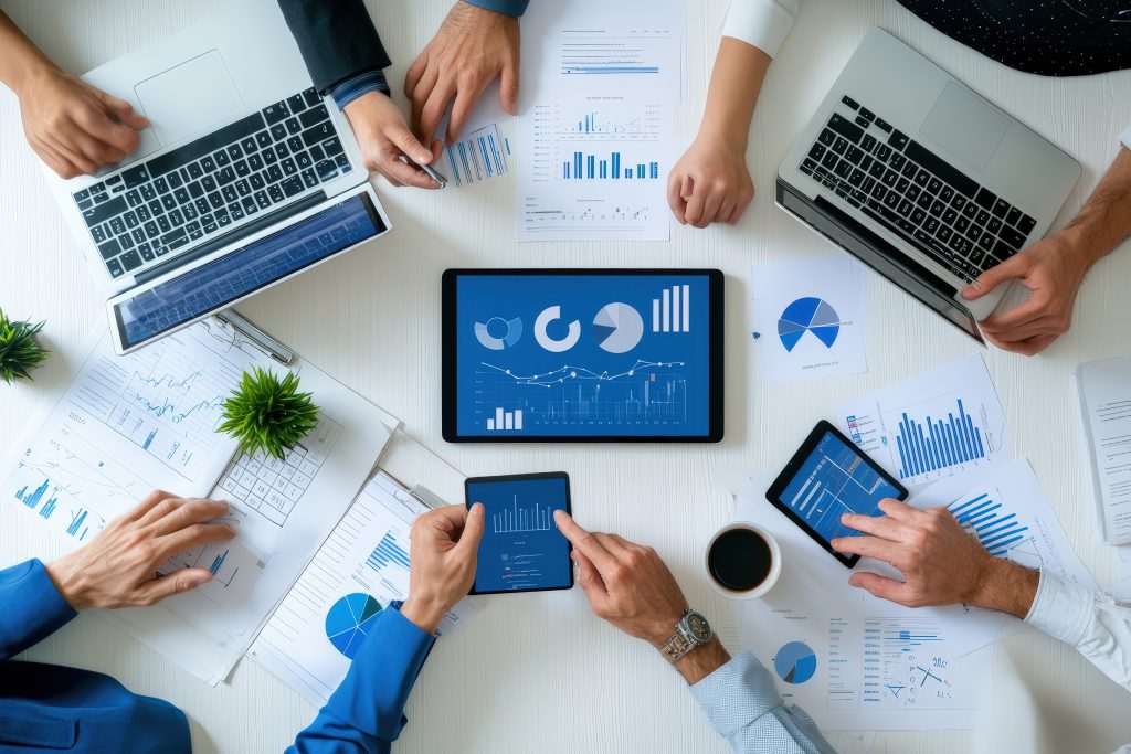 Um grupo de empresários analisando dados e gráficos em um tablet digital e laptops em uma mesa