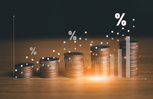 Pilhas de moedas e gráfico de porcentagens ascendente. Análise financeira detalhada, onde a Dedução de perdas fiscais pode otimizar resultados.