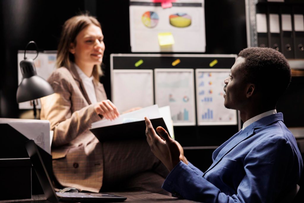 Empresários discutem documentos e gráficos em um escritório, realizando a due diligence de projetos importantes.