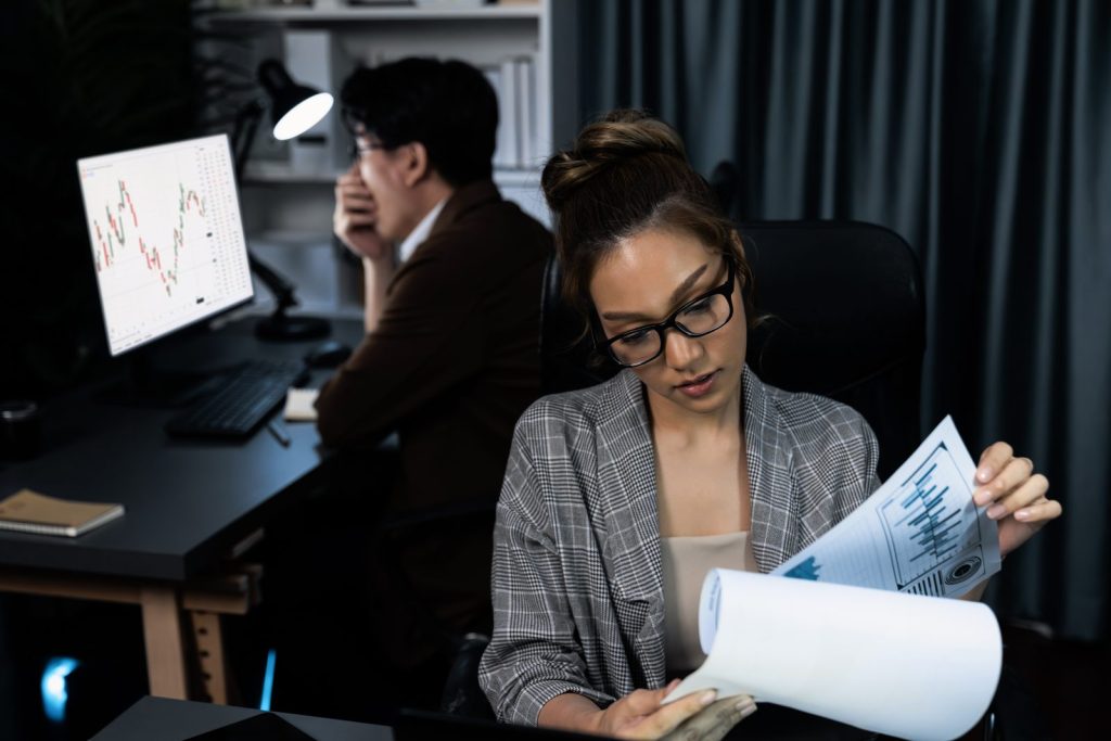 Analista de negócios lendo relatórios financeiros no escritório, preparando estratégia para recuperação extrajudicial ou reorganização empresarial. 