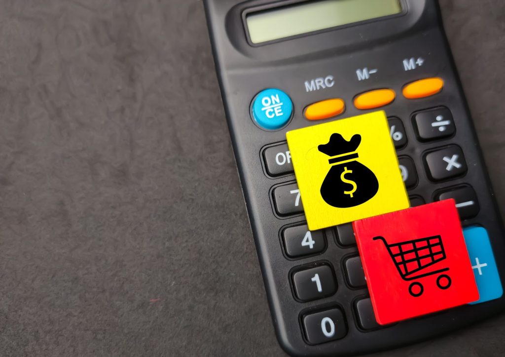 Calculadora com ícones de compras e dinheiro, representando o impacto do ICMS nas operações comerciais.