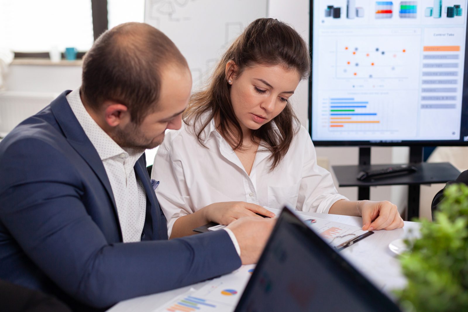 Profissionais analisando relatórios e gráficos em reunião sobre compliance tributário na gestão de riscos.