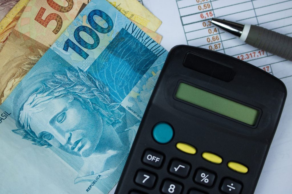 Notas de real, calculadora e planilha de valores ilustram os riscos do aproveitamento indevido de créditos tributários.