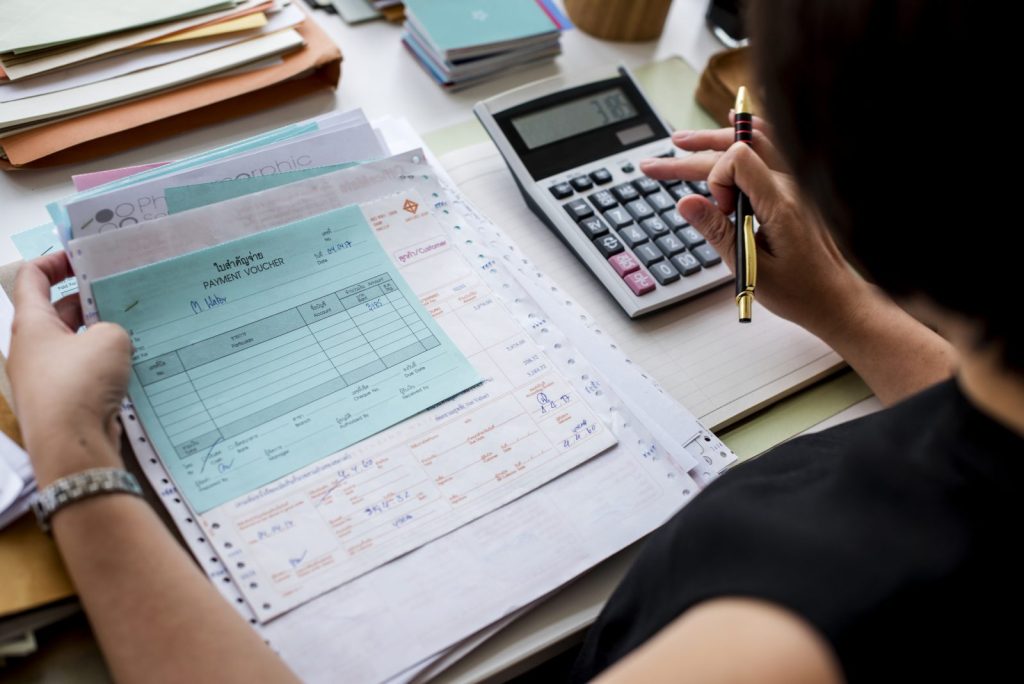 Profissional conferindo comprovantes de pagamento e calculadora, etapa comum na apuração da substituição tributária.
