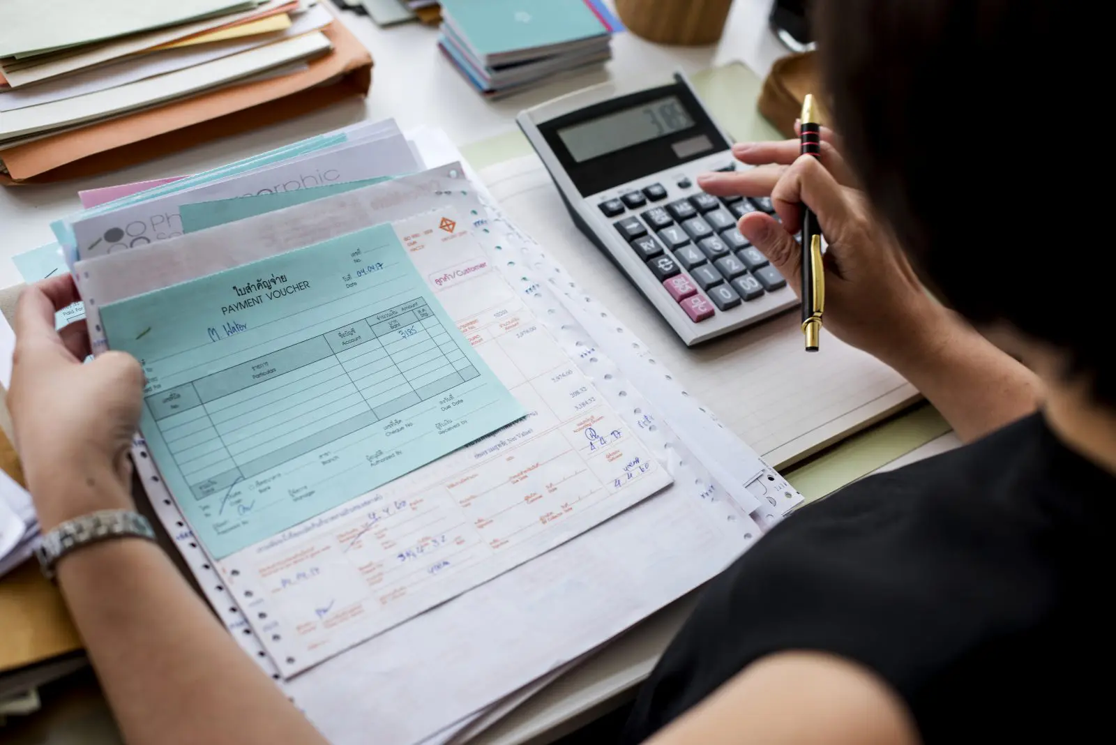 Profissional conferindo comprovantes de pagamento e calculadora, etapa comum na apuração da substituição tributária.